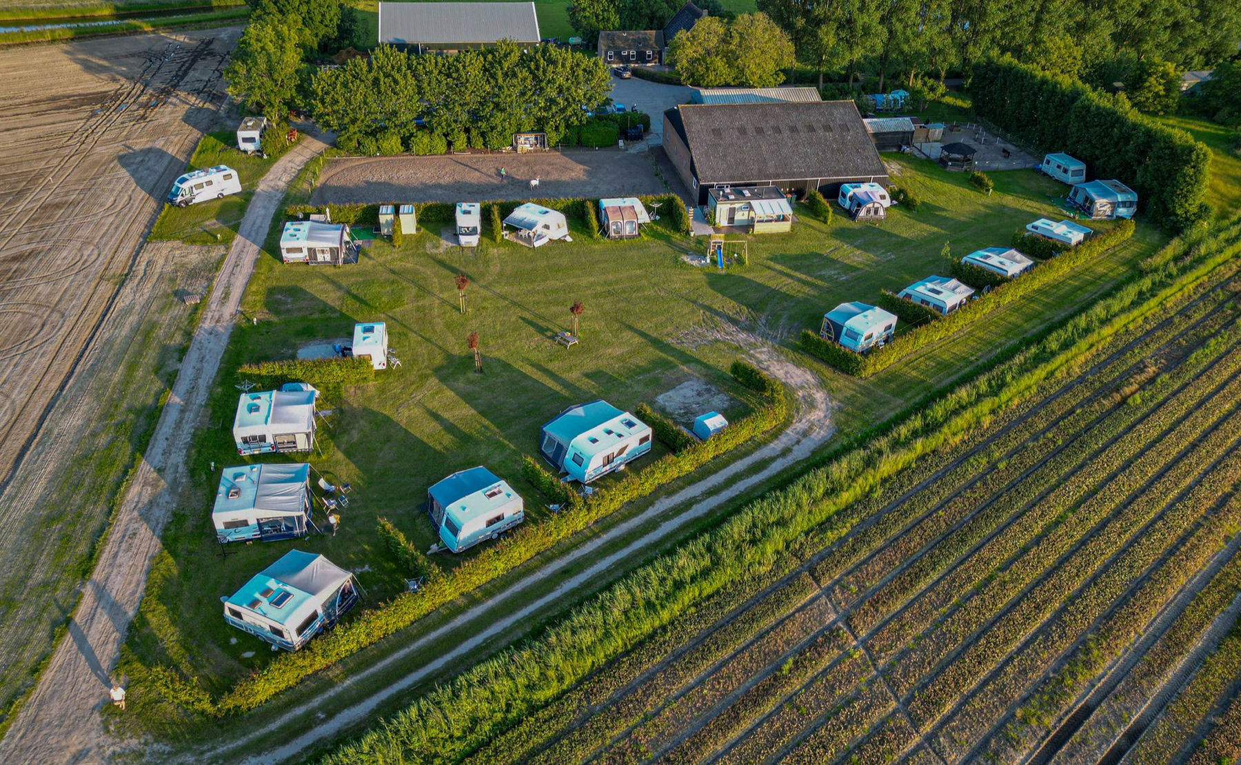 Luchtfoto van Boerderijcamping Mariëndreef tussen de akkers in West-Brabant in de avondzon