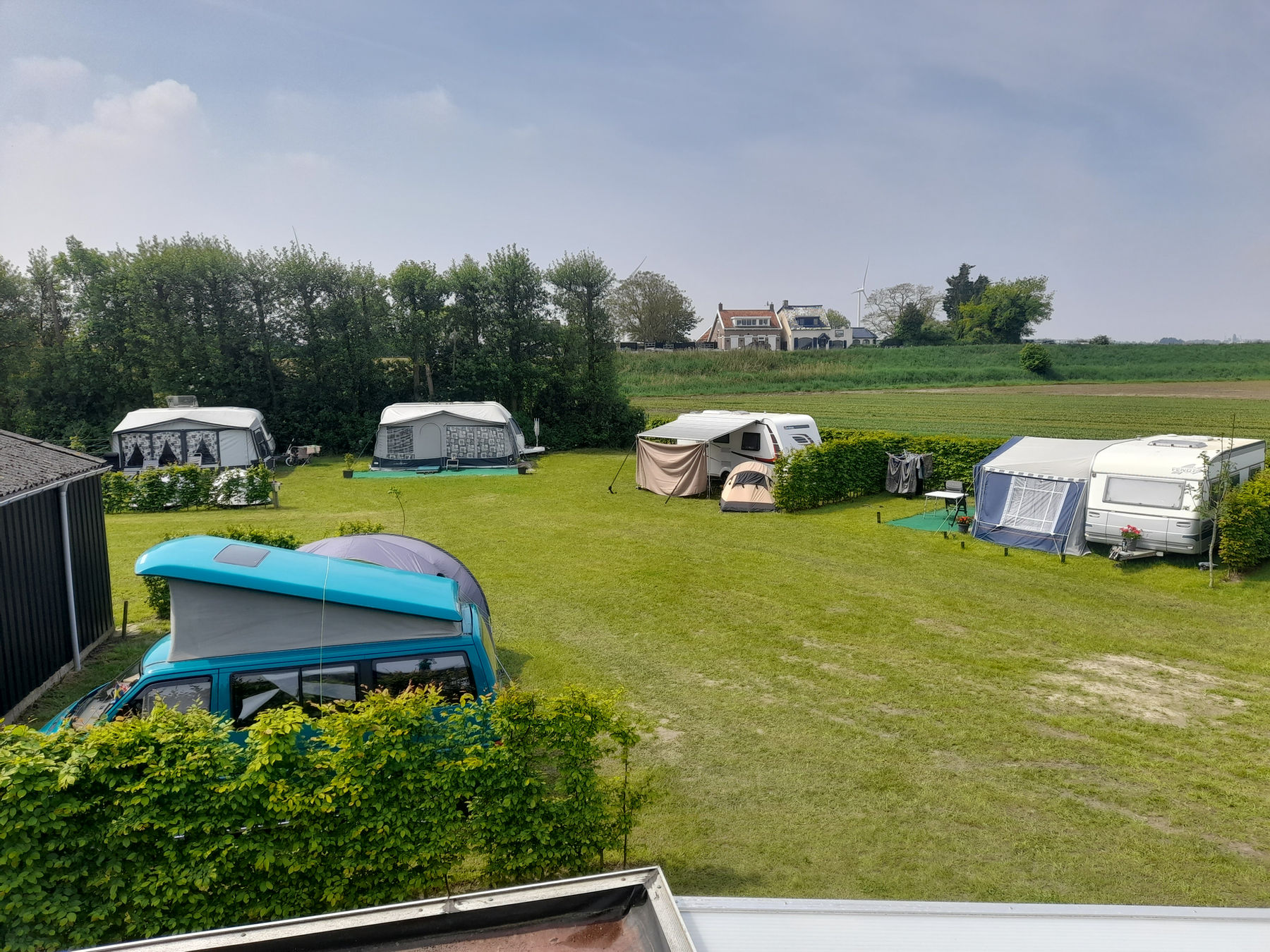 Tenten en caravans op het veld met zicht op de polder